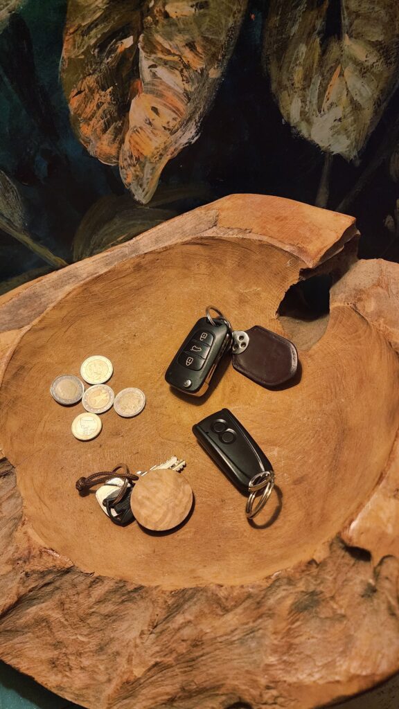 Hölzerne Schale mit ein paar Münzen, einem Autoschlüssel, einem Garagenschlüssel und einem Haustürschlüssel